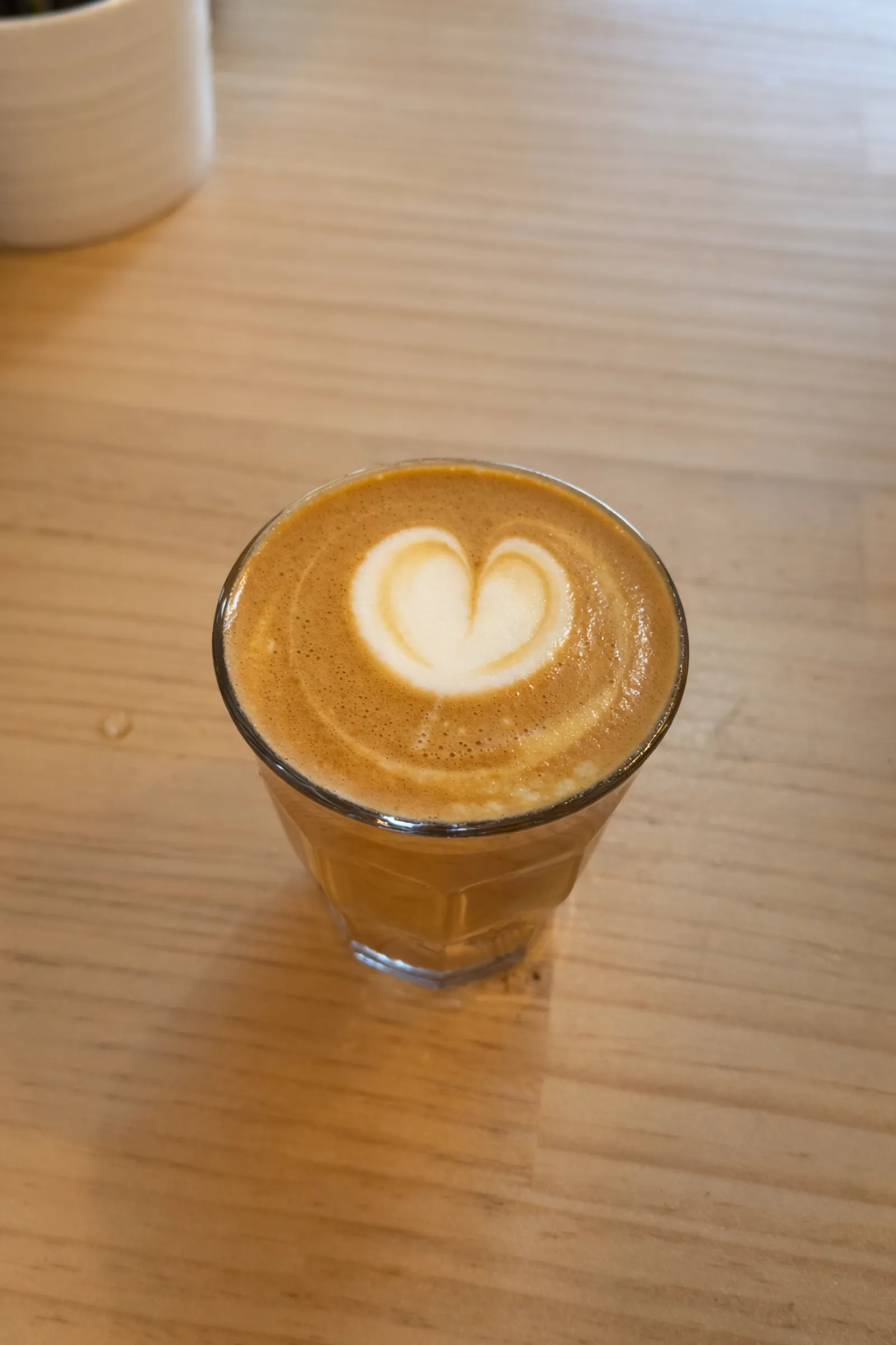 Glass of coffee with heart latte art on a timber table